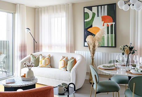Image of a living room within a Kidbrooke Village showhome. The room feels airy with lots of natural light, and shows a sofa and dining area.