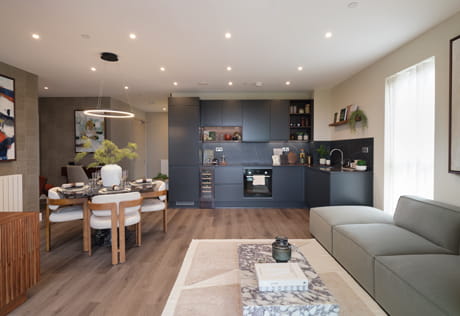 Modern designed living space with sofa and coffee table, dining space and kitchen in background.