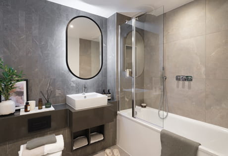 Bathroom with shower over bath, beige and grey walls, wash basin with mirror and halo lighting and shelving.