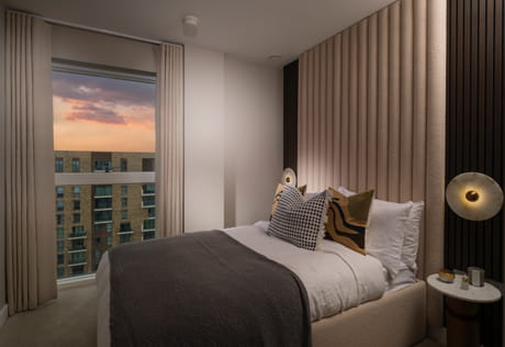 Bed with contemporary design, bedside tables and tall window for ample natural lighting.