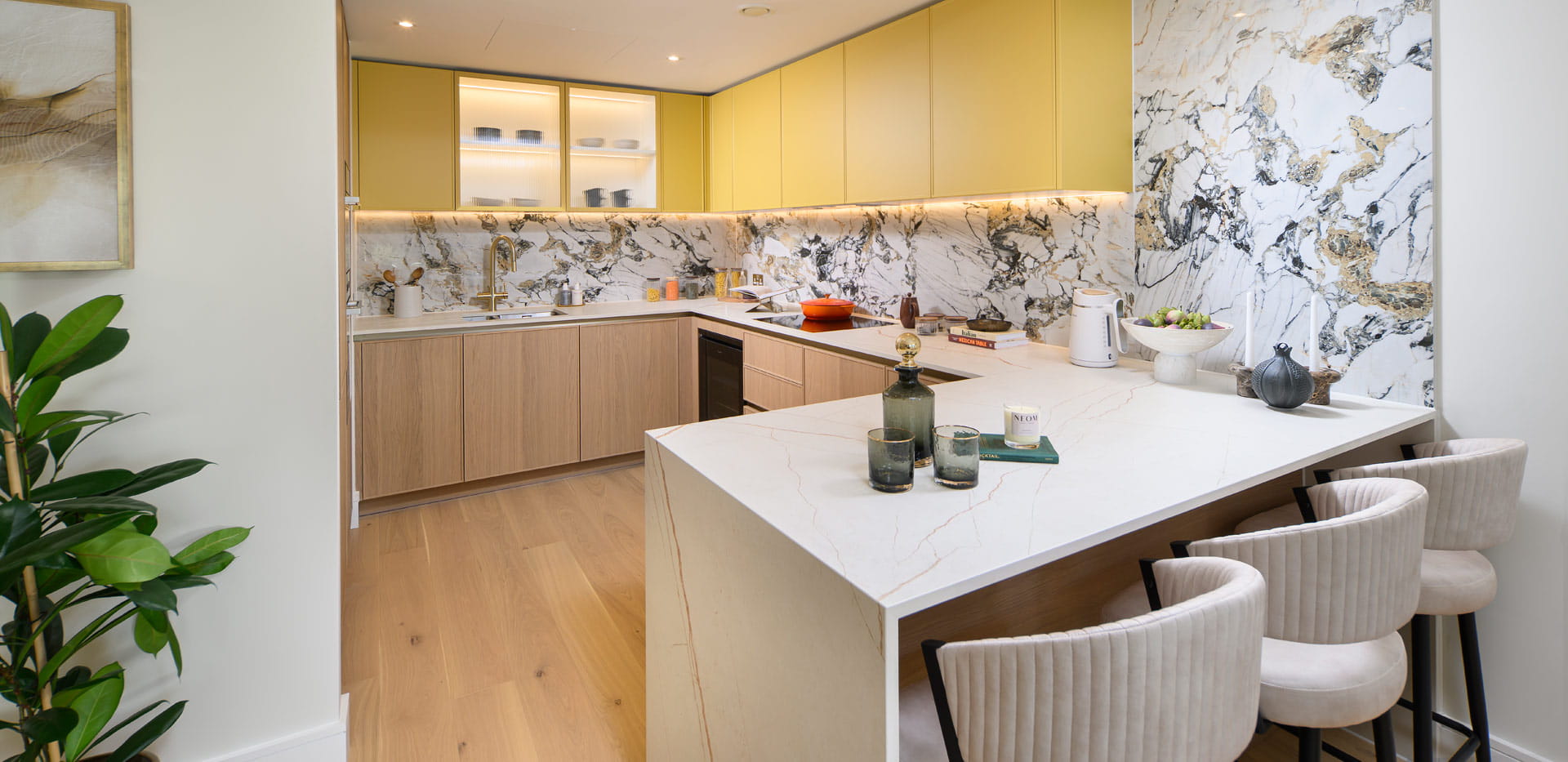 White-topped kitchen island in foreground, kitchen with marble pattern splashback walls