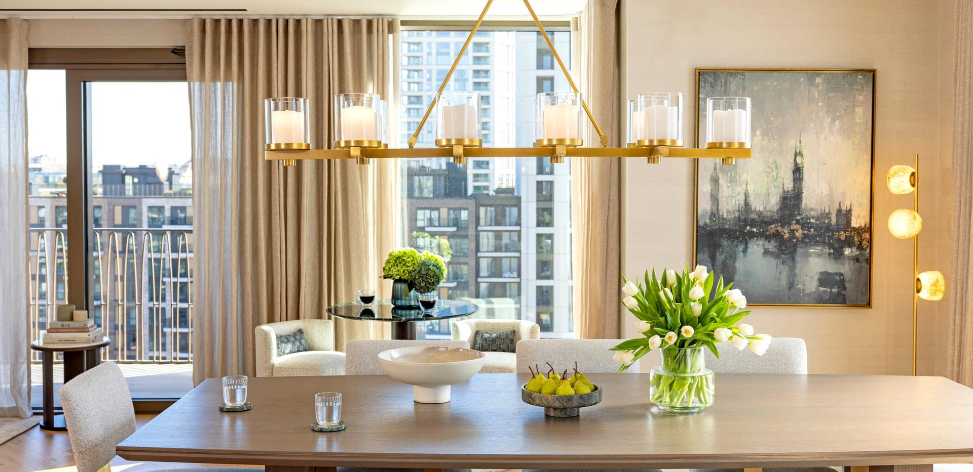 Long, wooden dining table with decorations on top, with linear chandelier lighting, low-hanging, above