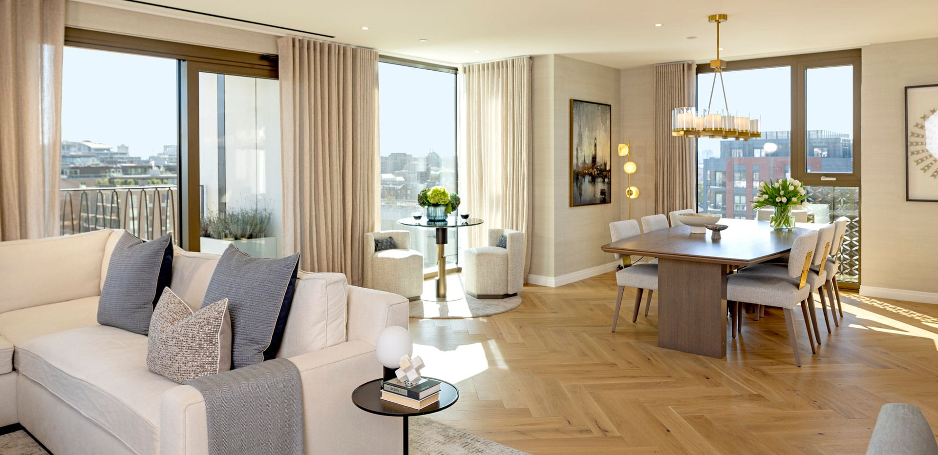 Partial view of sofa, herringbone wood flooring design, wall hangings, with dining table in background