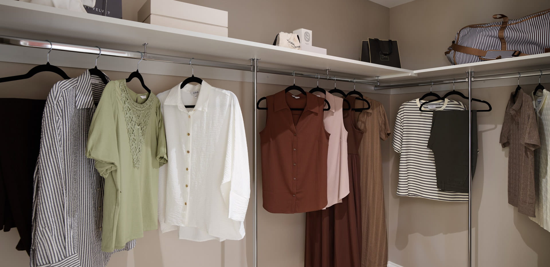 Closeup of walk in wardrobe clothes hanging and upper shelving space.