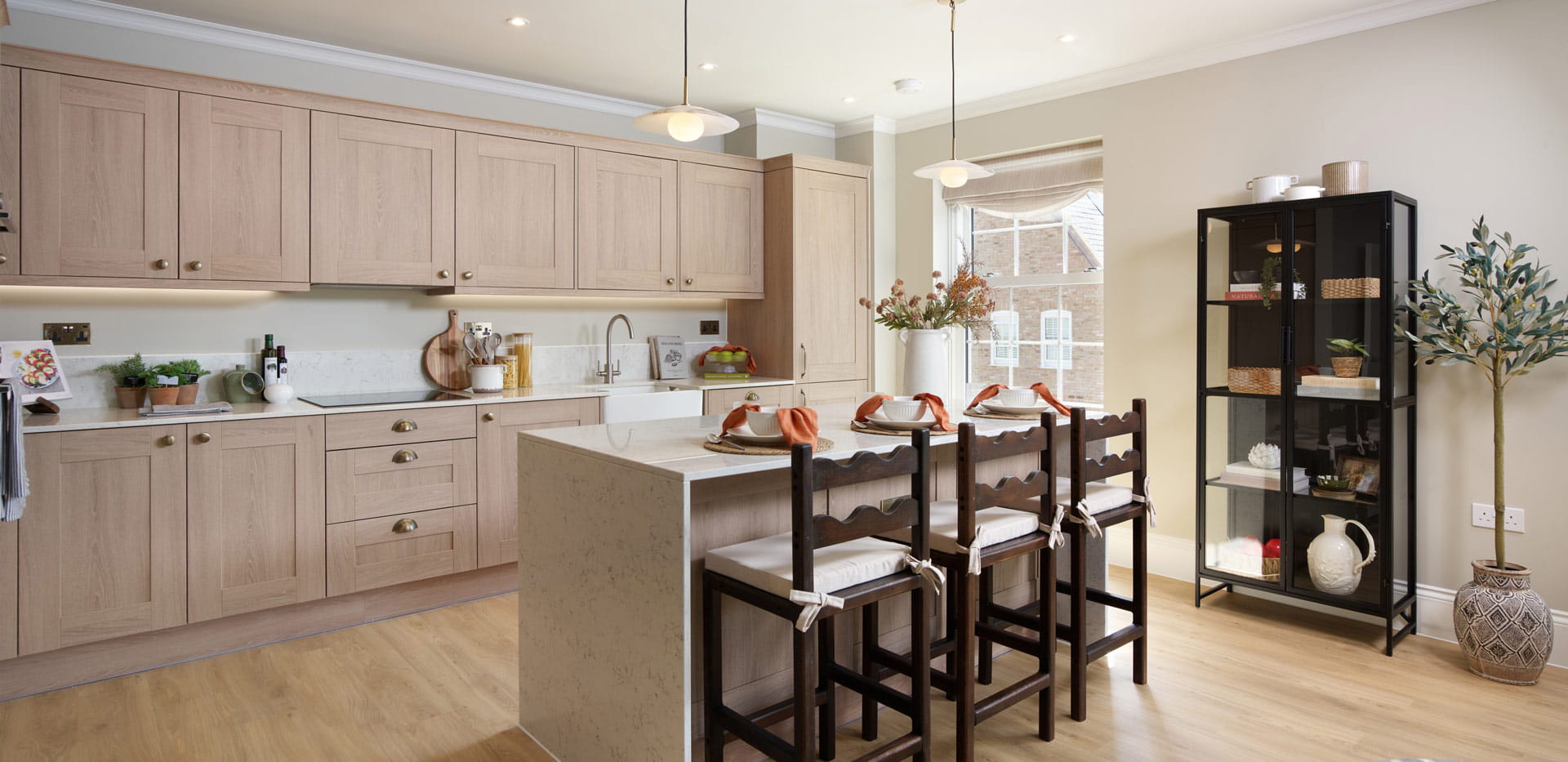 Kitchenette with breakfast island, beige cupboard panels and white countertops.