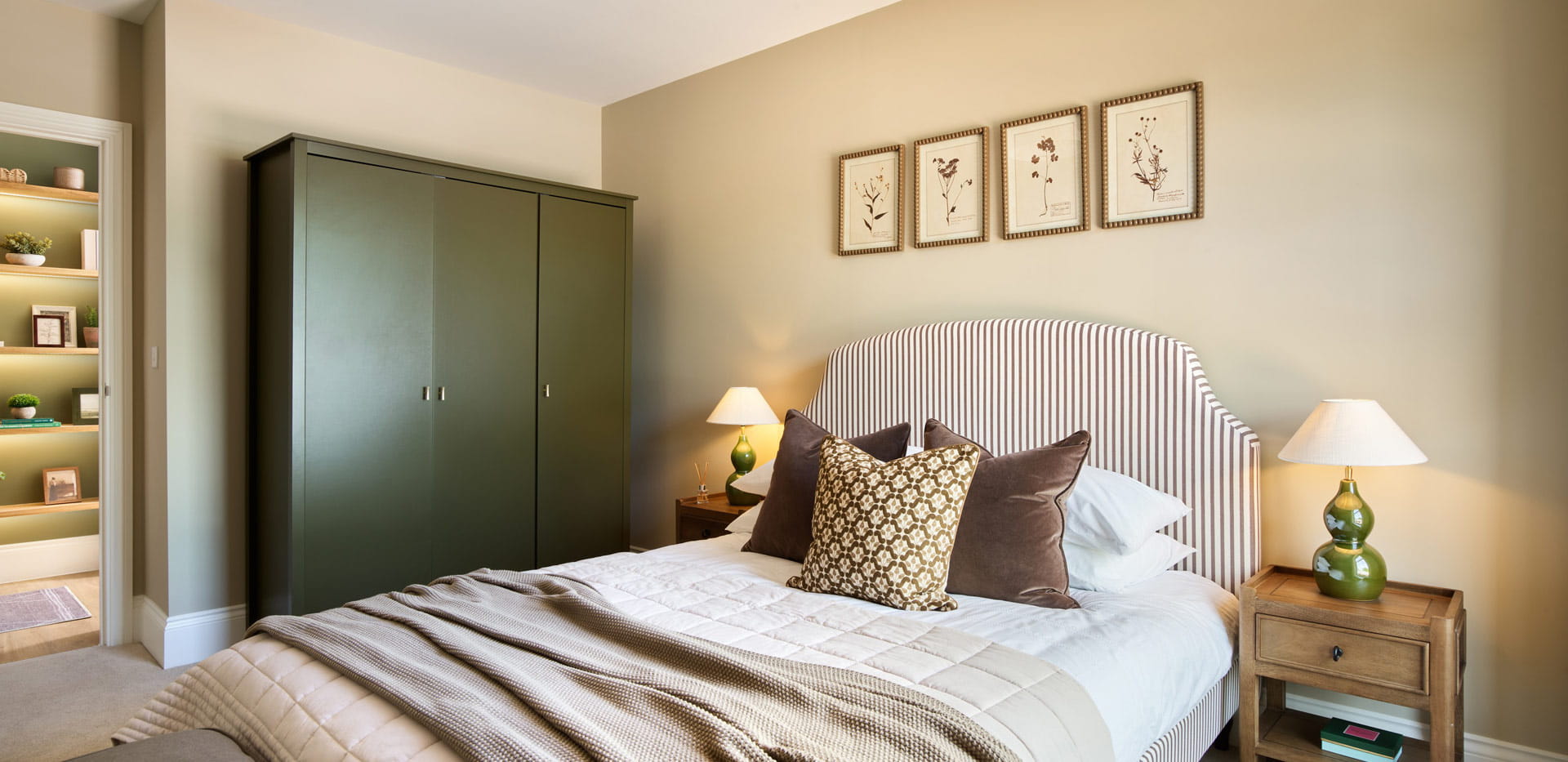 Closeup of made-up double bed and bedside tables, wardrobe, wall hangings.