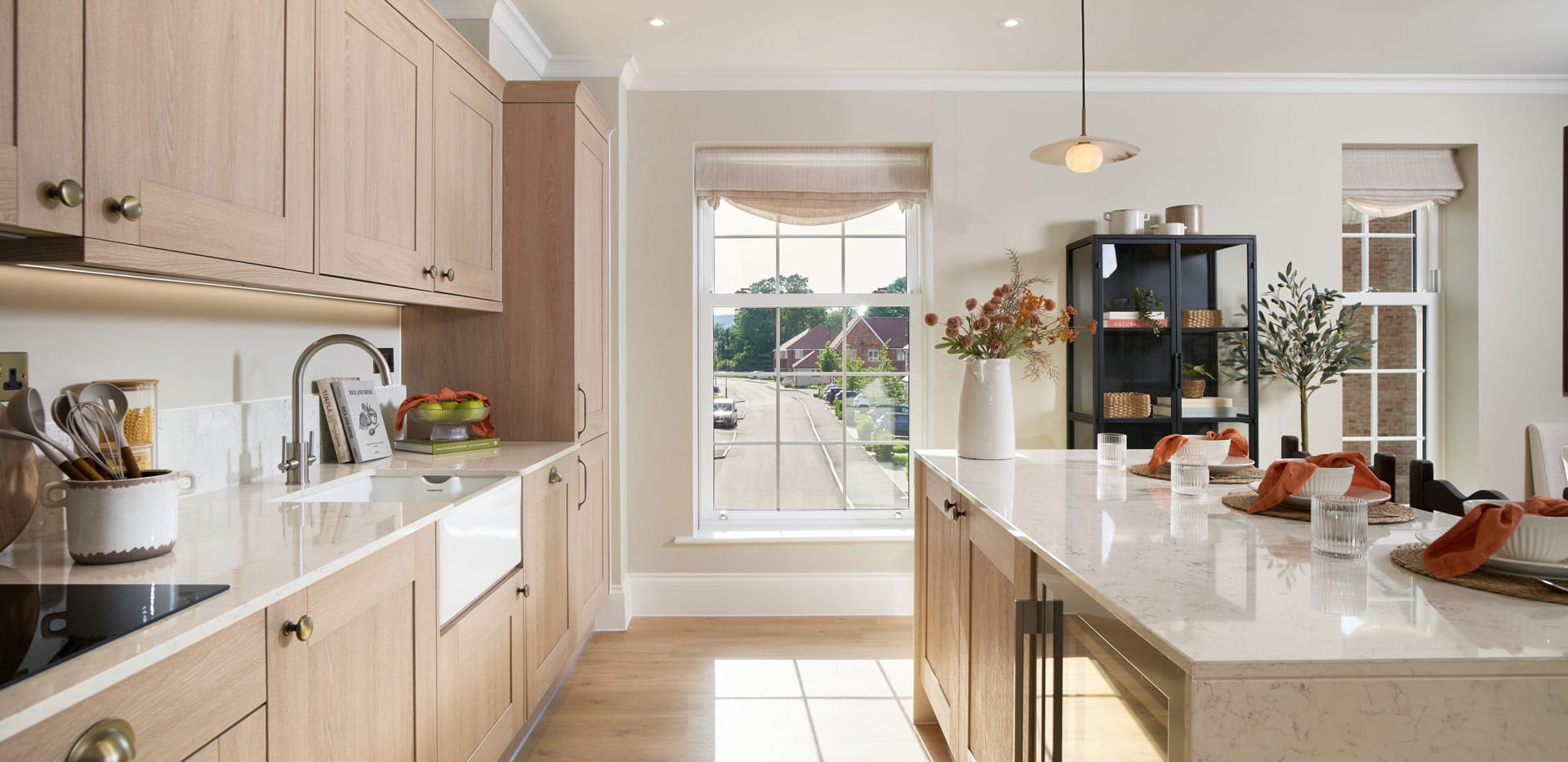 Closeup of kitchen and breakfast island, beige cupboards, white countertops, modern comfort appliances.