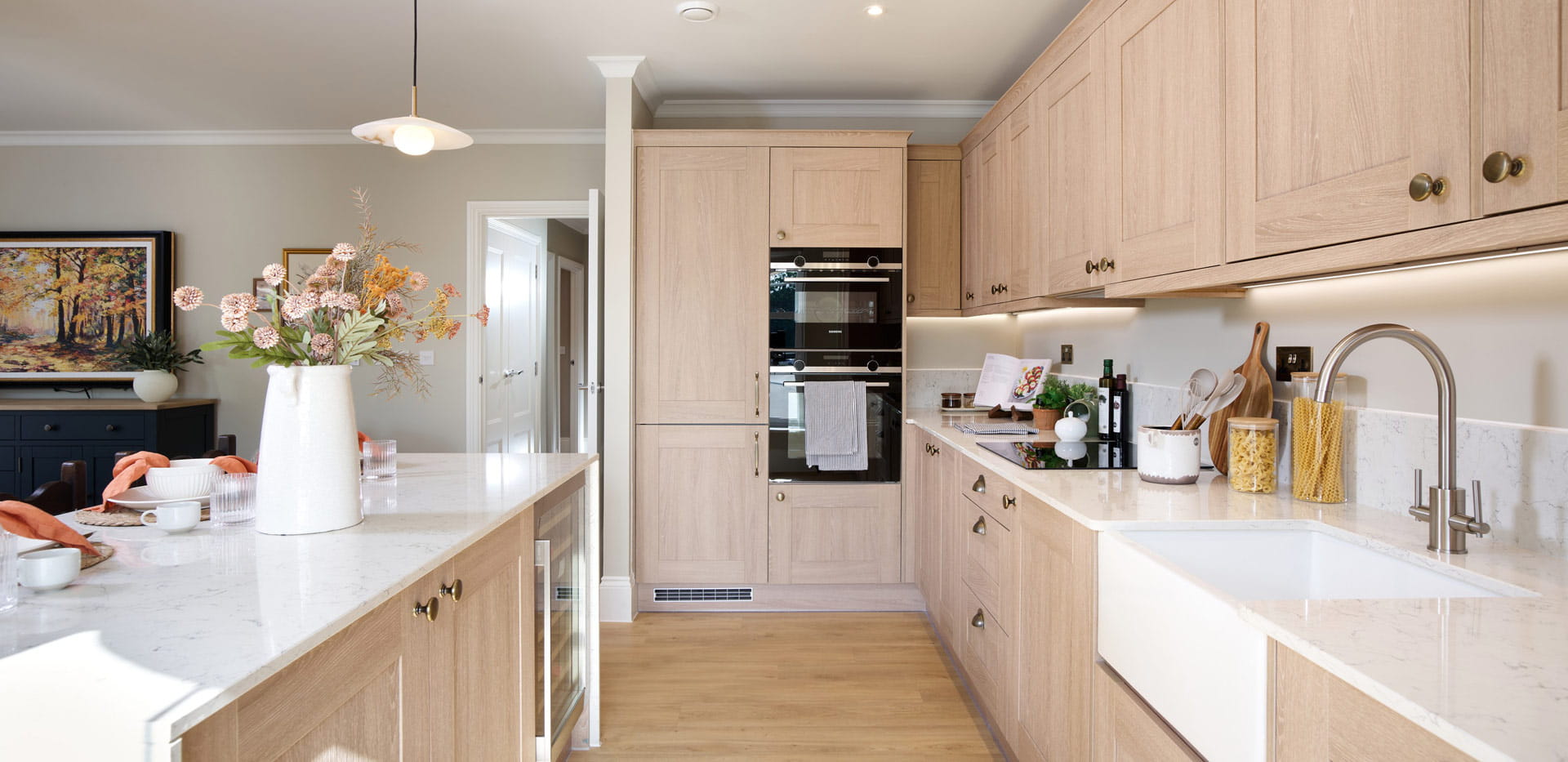 Closeup of kitchen and breakfast island, beige cupboards, white countertops, modern comfort appliances.