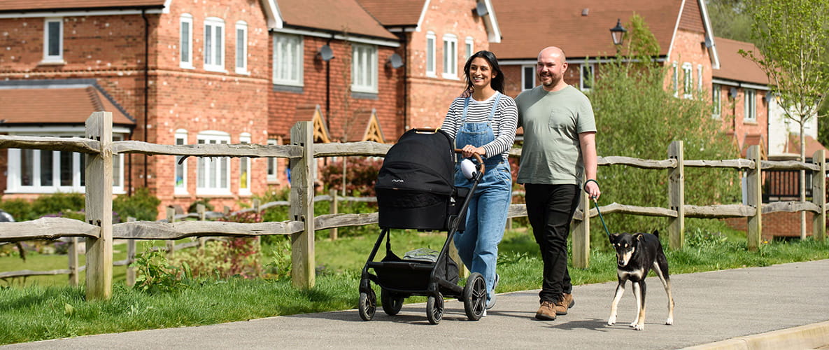 Image of a couple pushing their baby down a street