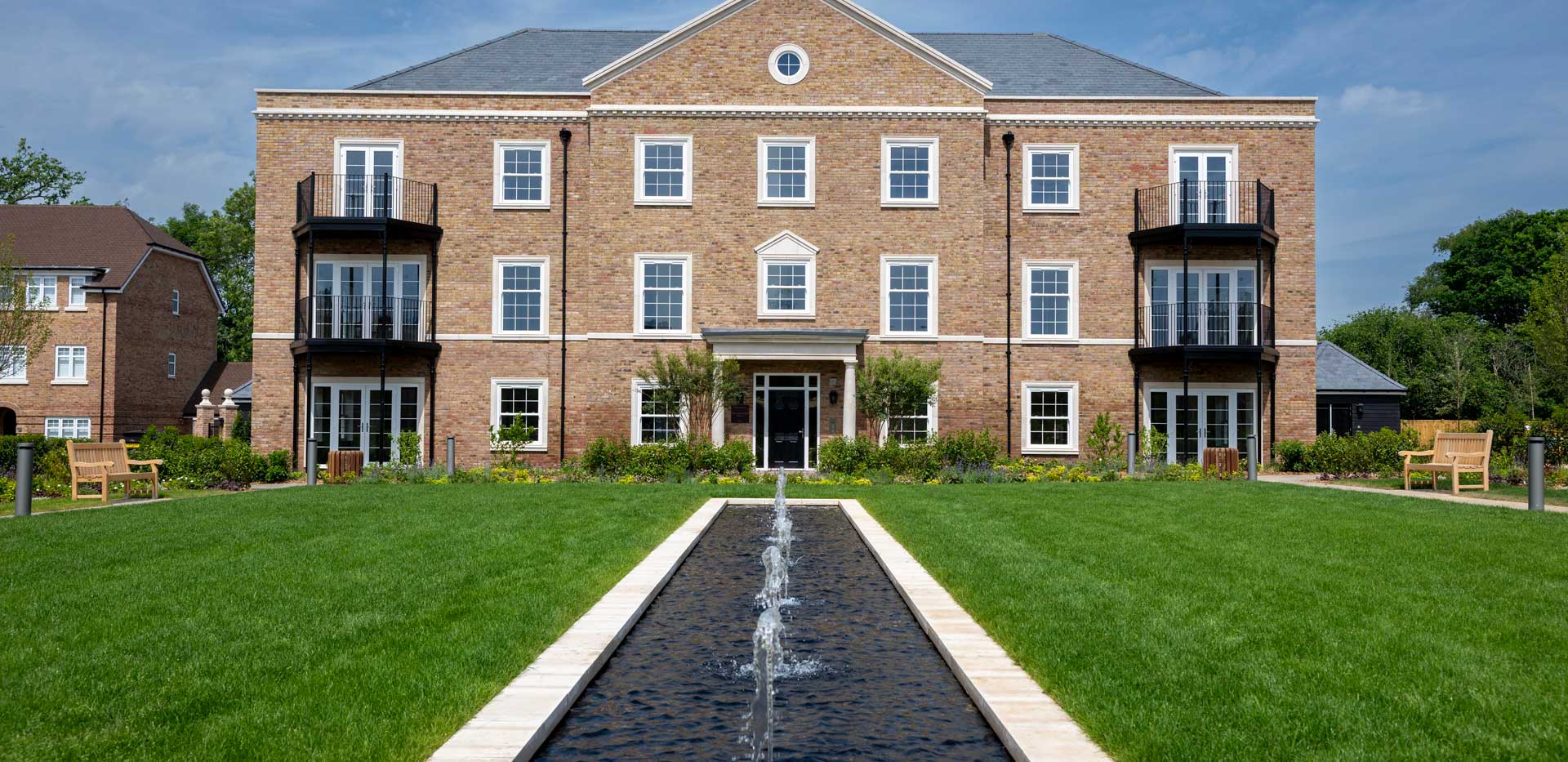 CGI of external development housing, central water feature, mowed lawns.