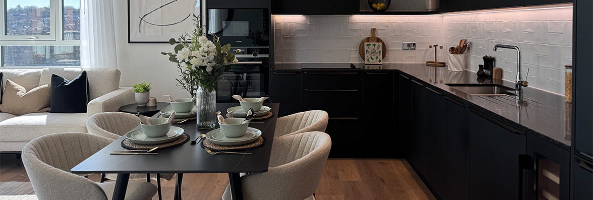 Modern designed living/dining space and kitchen with black cupboards and countertops.