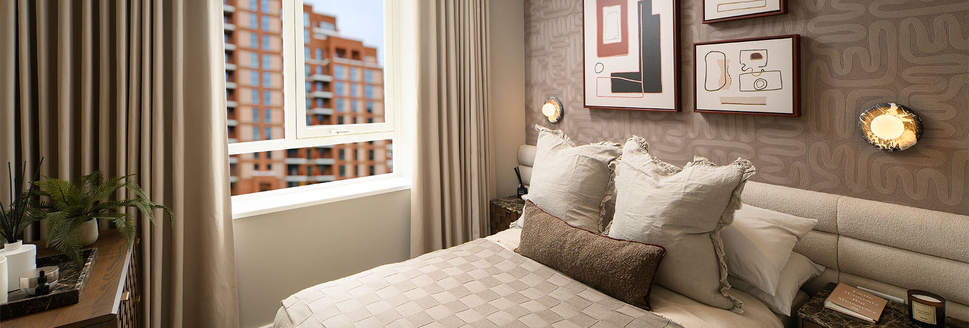 Modern beige bedroom with a double bed, abstract wall art, bedside tables and a window overlooking flats.