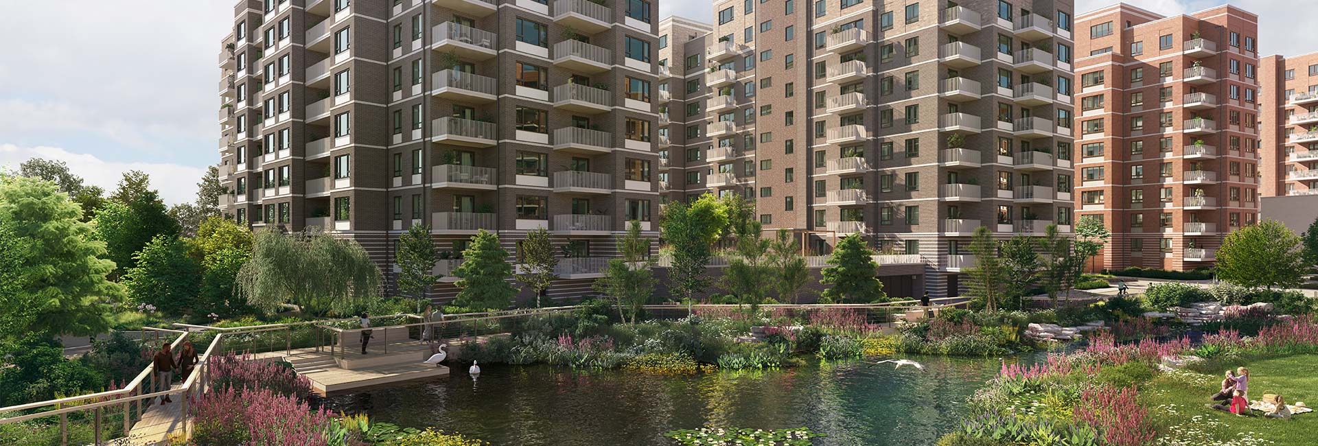 Modern apartment blocks overlooking a landscaped pond and gardens, with a footbridge and cyclist in the foreground.