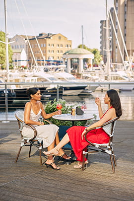 An image of two women enjoying a drink at St Katherine Docks