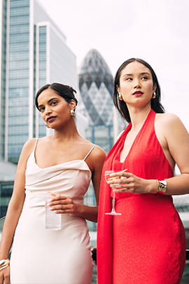 An image of two women posing for a photo in front of The Gherkin