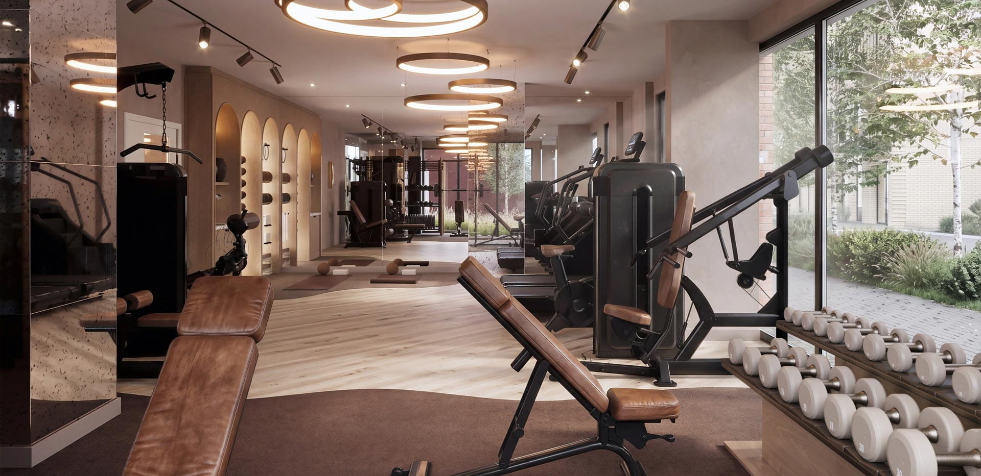 View down a long gym room with floor mats, exercise cardio and weights machines.