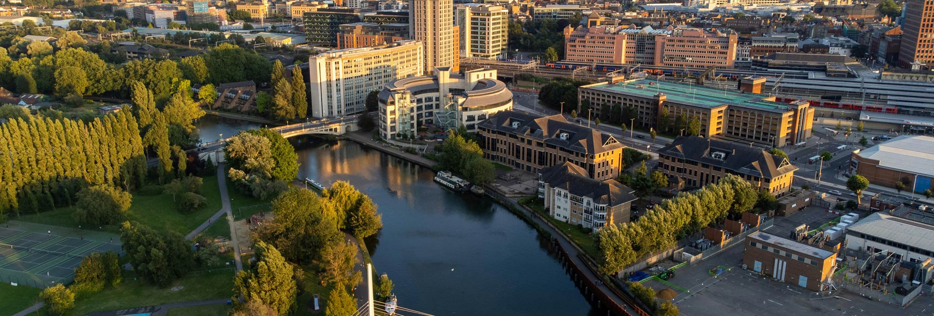 CGI oblique aerial view of a river with landscaped banks and new build apartment blocks adjacent.