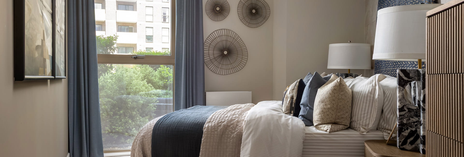 View of a side of bed, with wall hangings, decorated room with royal blue and off-white tones.