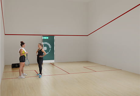 Two women with squash rackets chatting on an indoor squash court with pale wood flooring and high ceiling lights.