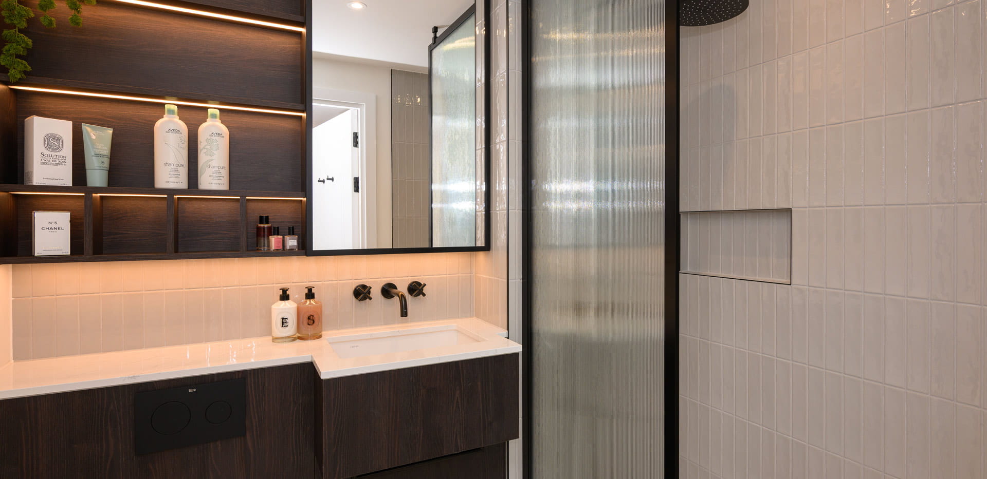 Modern designed bathroom with shower unit, wash basin with wall mirror, black and white details.