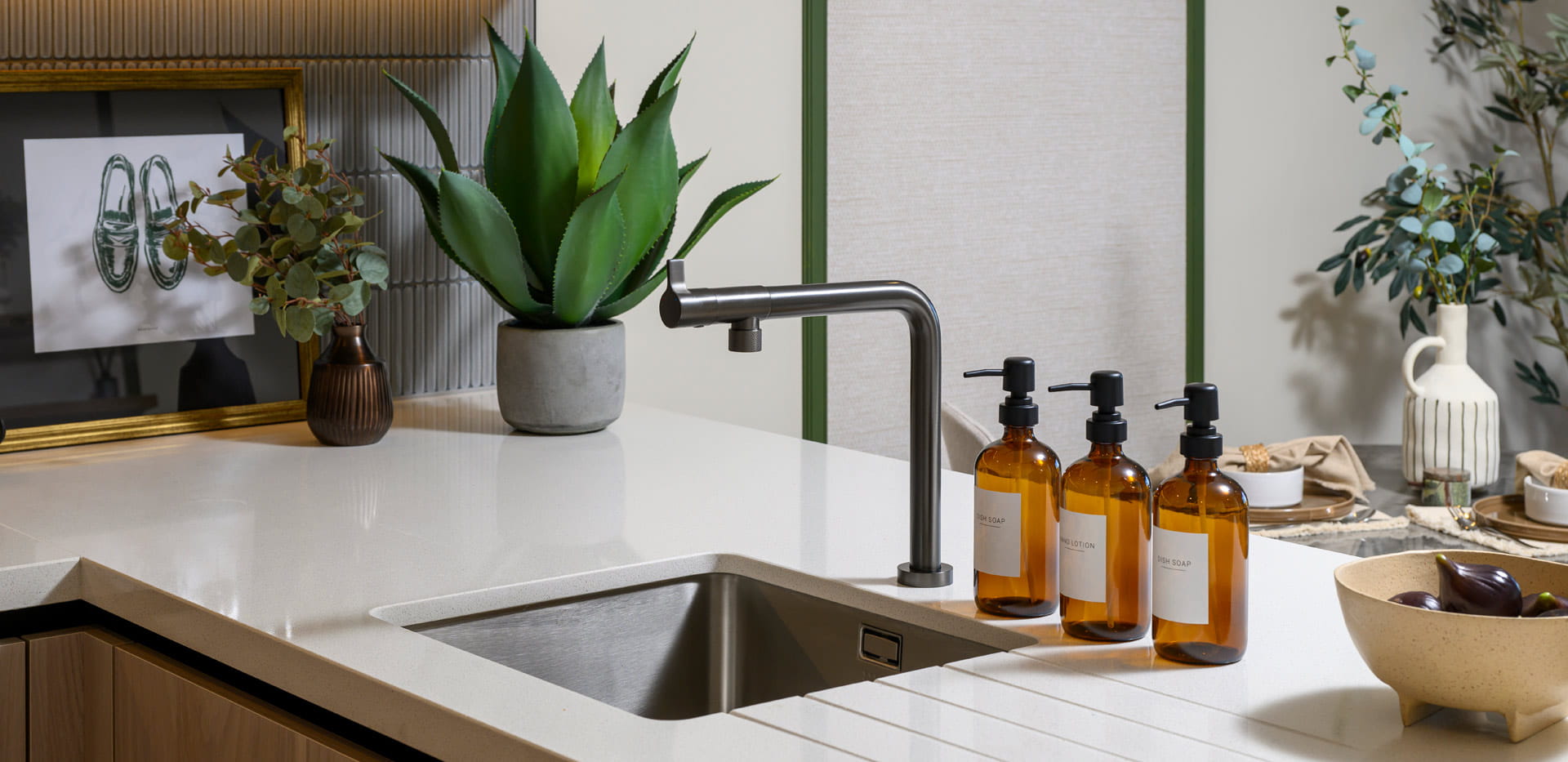 Closeup of kitchen sink with off-white countertops, kitchen decorations.