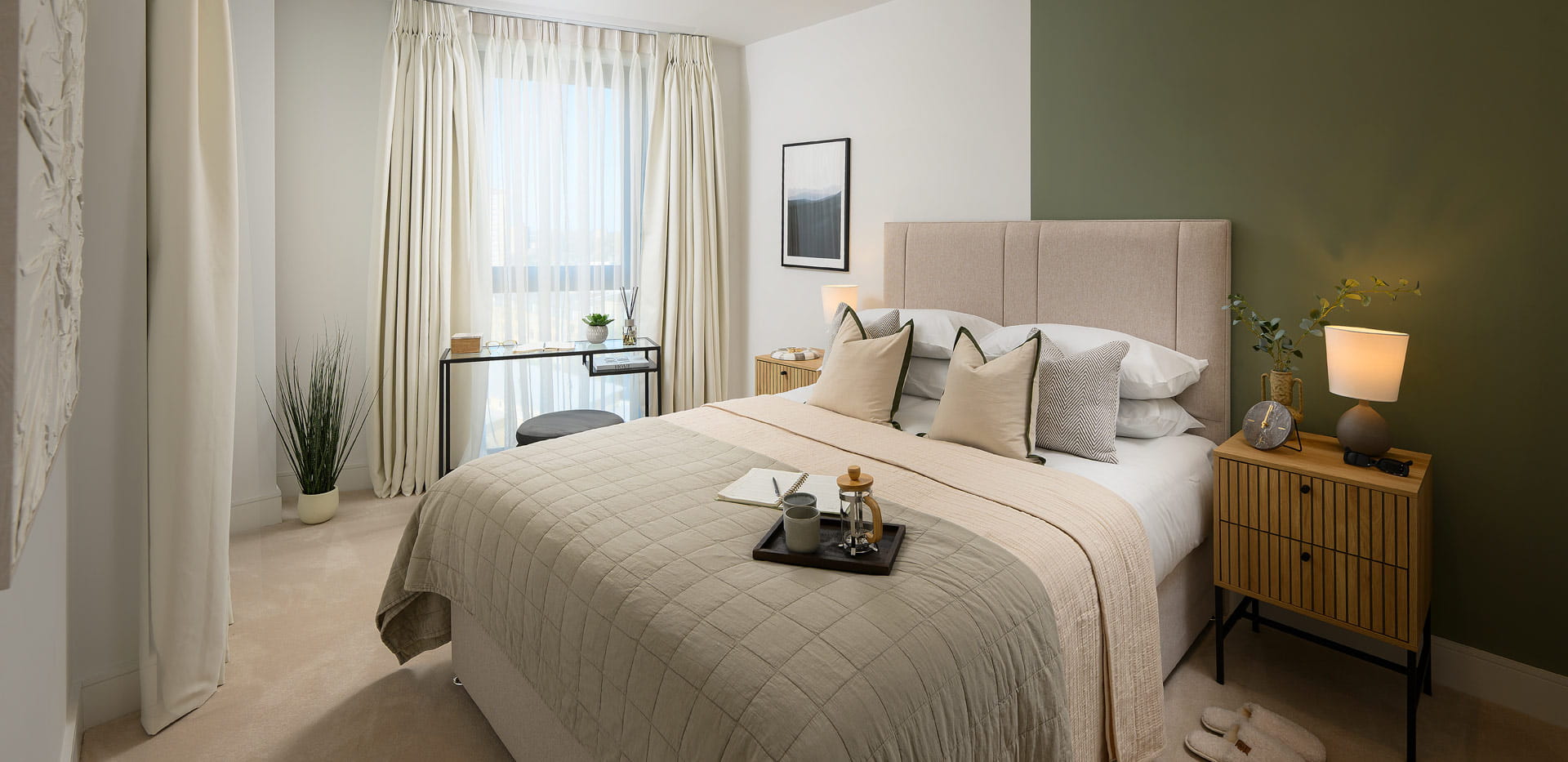 Double bed with contemporary design, bedside tables, white and moss green tones, full height curtains.
