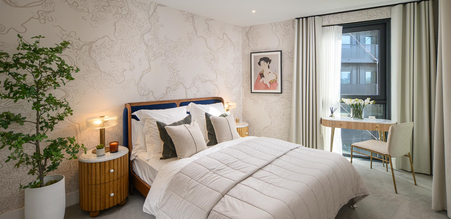 Double bed with contemporary design, bedside tables, indoor plant, light tones, small table beside window.