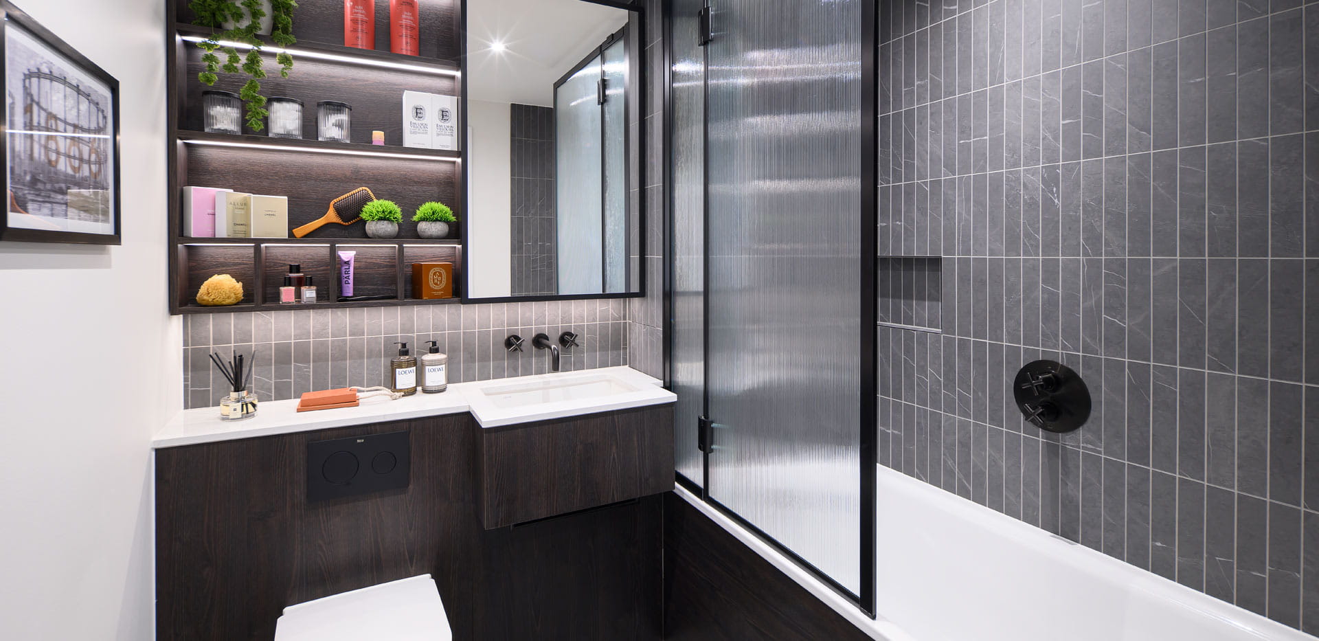 Bathroom with shower over bath, grey tiling, wash basin with cabinet mirror and shelving.