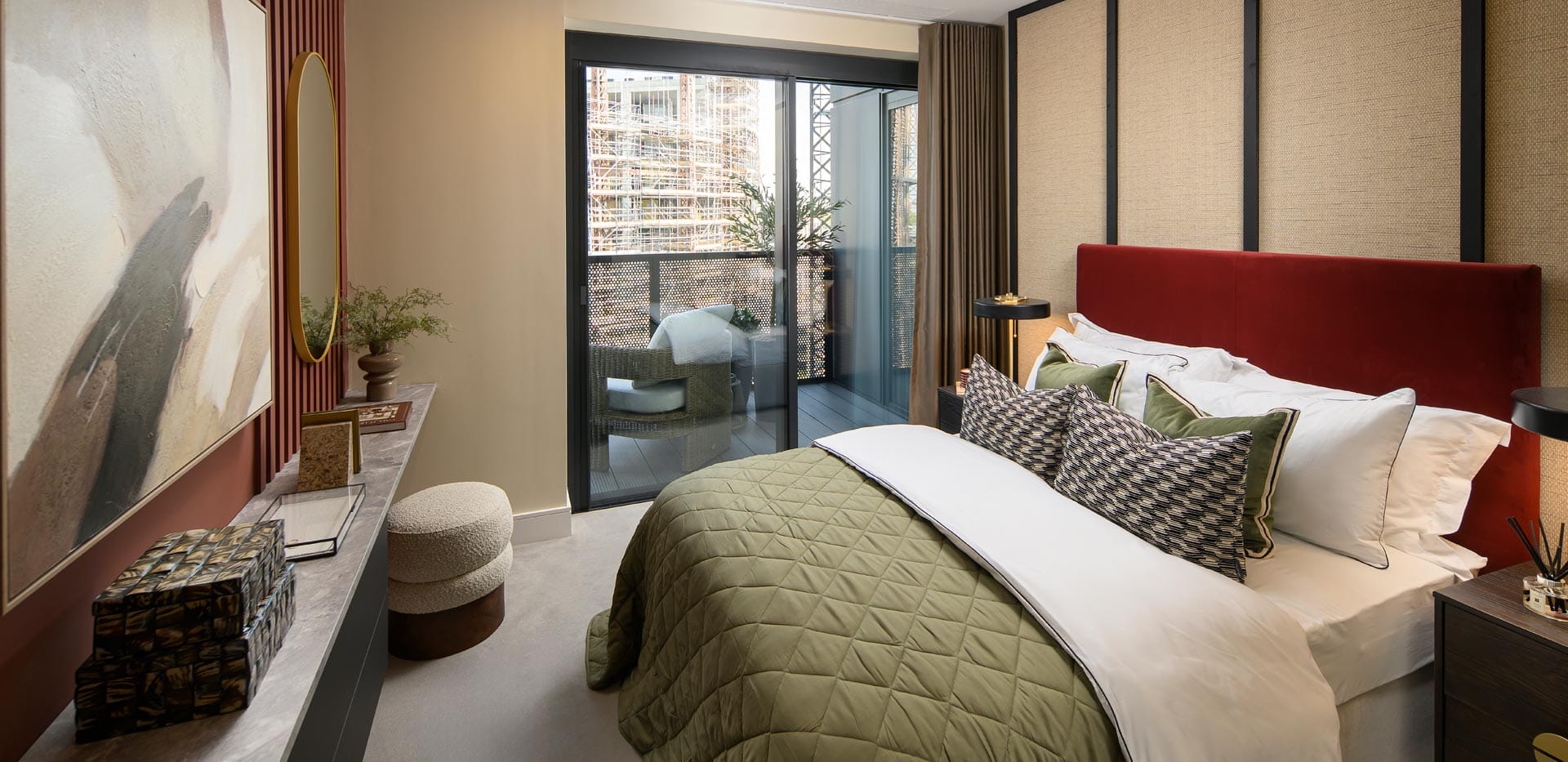 Modern bedroom with a red upholstered headboard, olive quilt, bedside tables and glass doors to a small balcony.