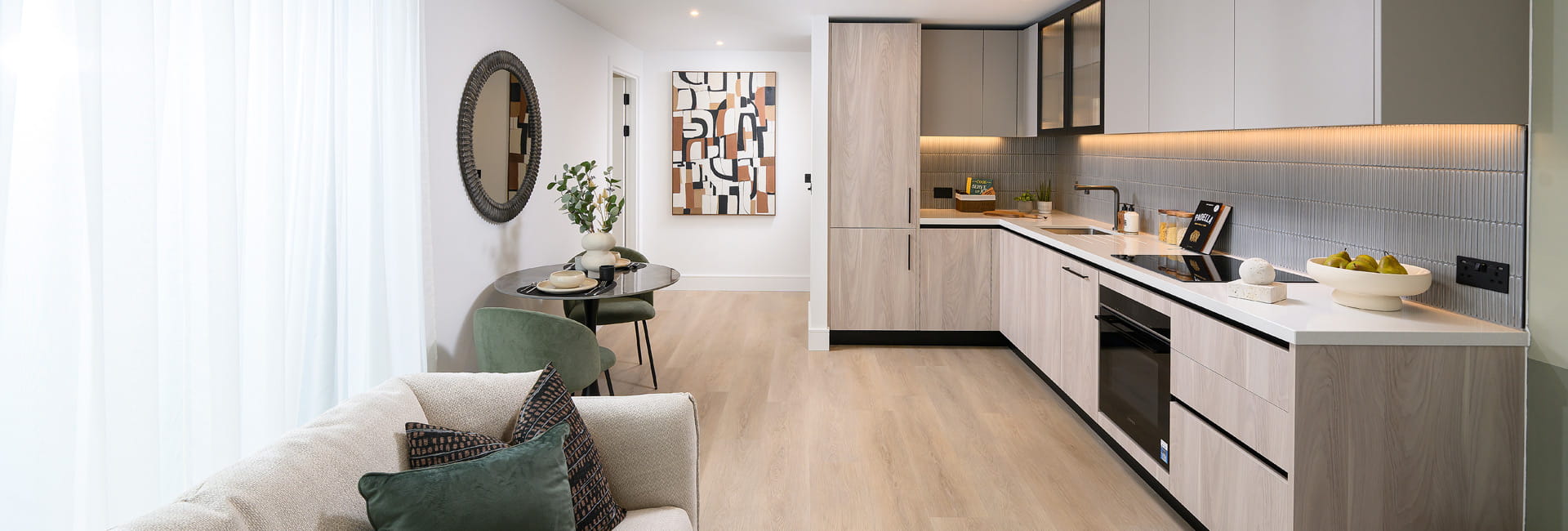 Kitchenette with light brown grey surfaces, white countertops, strip lighting and light grey splashback tiles