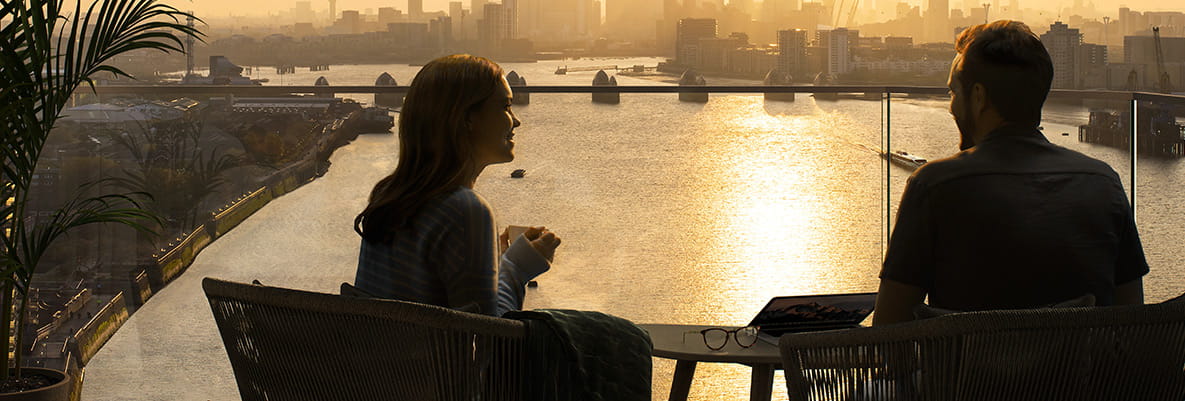 Couple enjoying the riverside view from their Royal Arsenal Riverside balcony