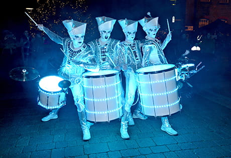 An image of people dressed in white with glowing drums