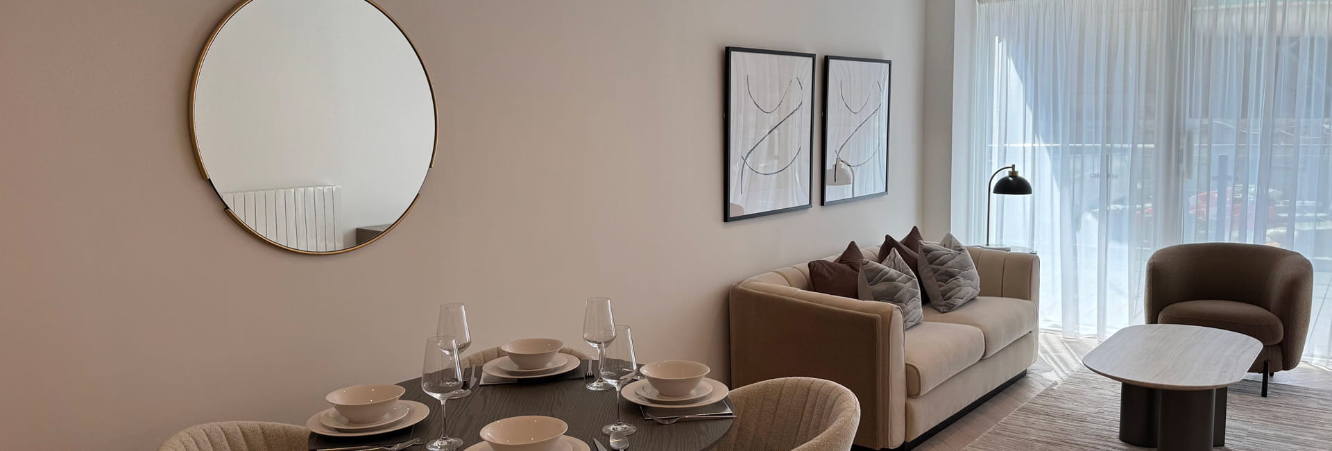 Circular wall hanging mirror, decorated dining table, living space in background.