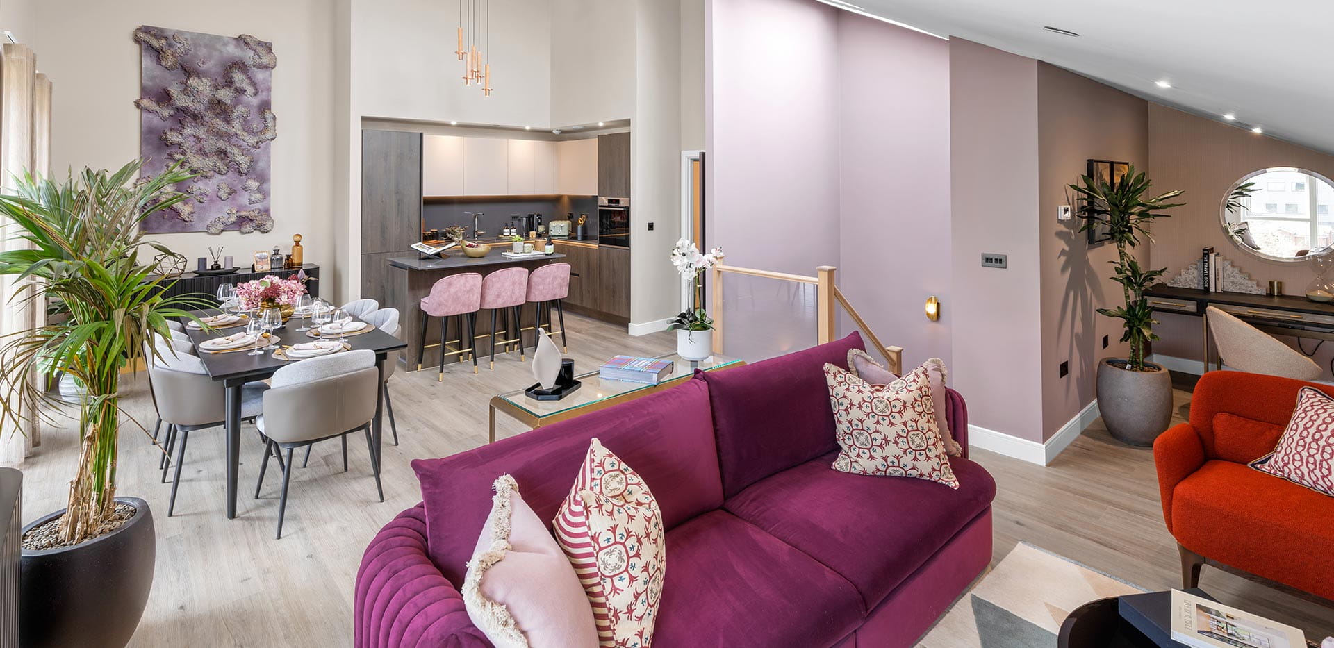 Living area with coffee table and vibrant, brightly coloured sofas with dining and kitchen areas in the background