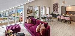 Living area with coffee table and vibrant, brightly coloured sofas with dining and kitchen areas in the background