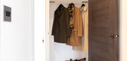 Wardrobe space with brown door and several coats inside