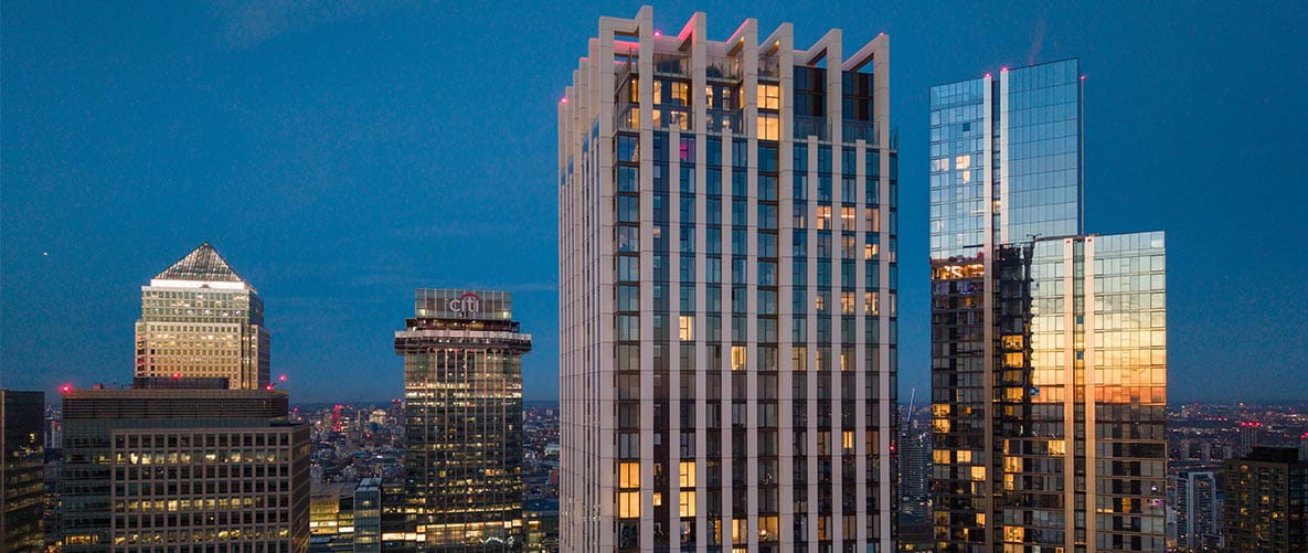An exterior photograph of South Quay Plaza with the London View in the background at Night