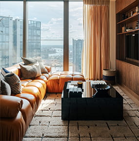 Modern designed living space with sofa and coffee table, tall windows with ample natural lighting.