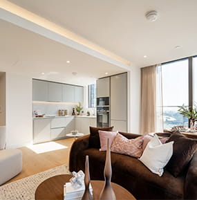 Modern designed living space with sofa and coffee table, tall windows with ample natural lighting.