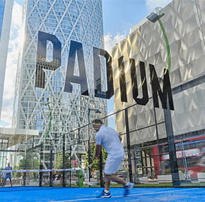 Man playing court-based sport at street level with the word Padium above