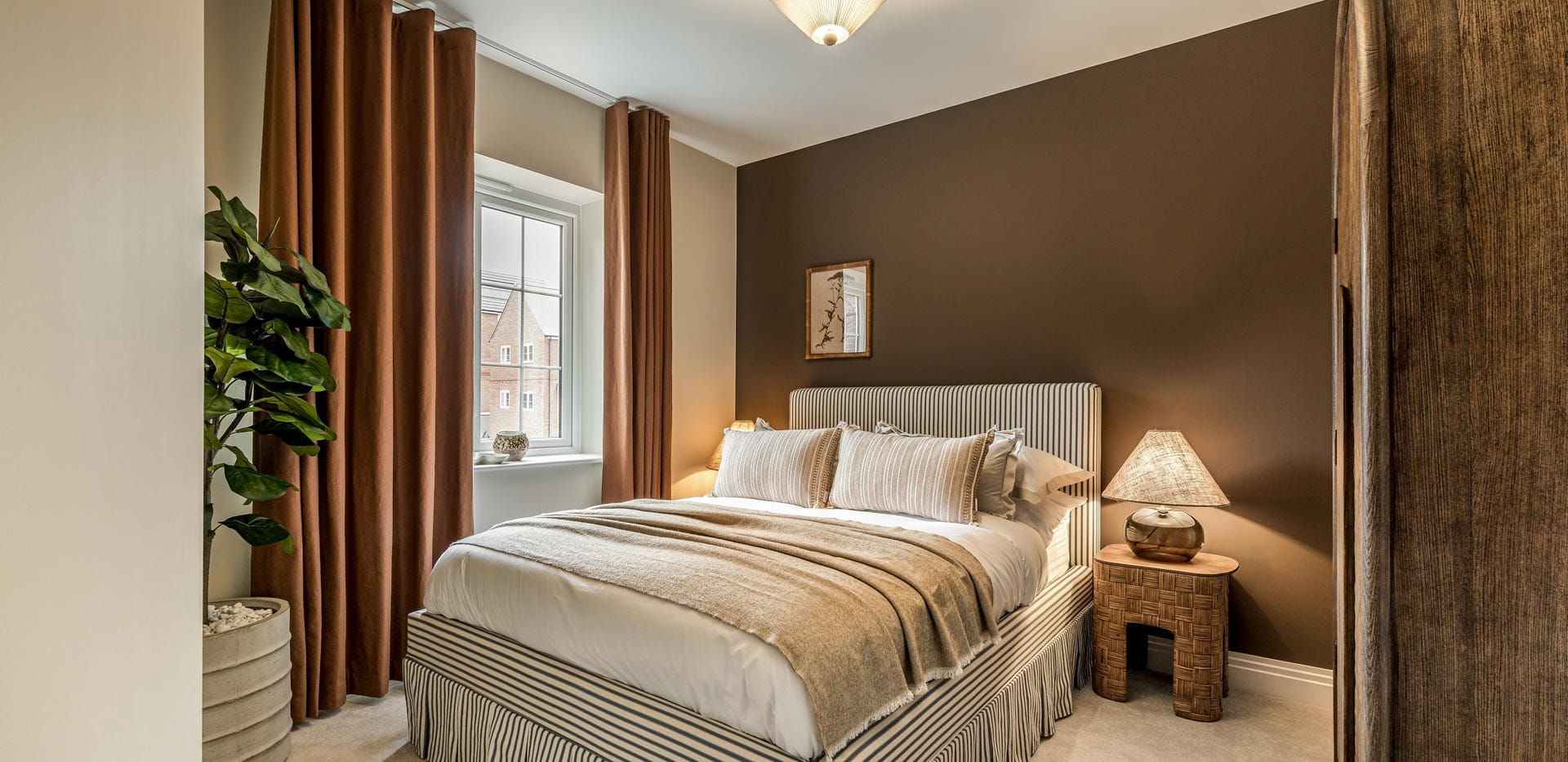 Double bed, beige and brown walls, copper-colour curtains and beige carpet