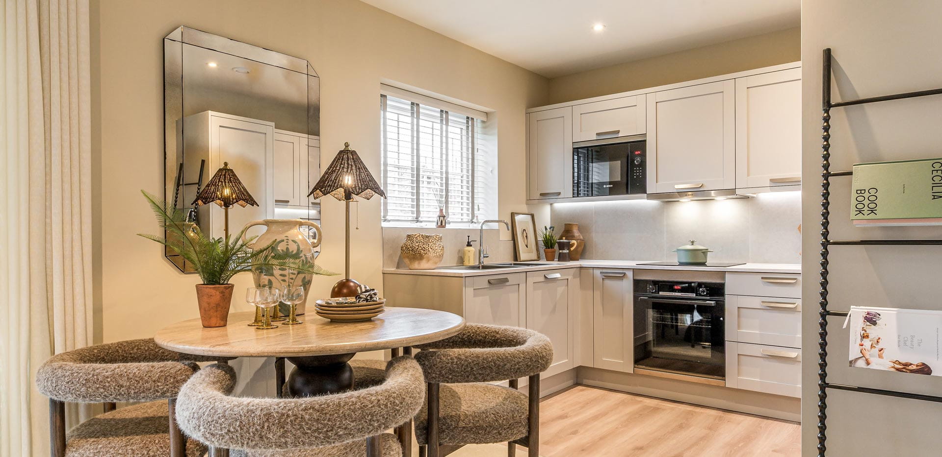 Circular dining table, newspaper rack and kitchenette in background