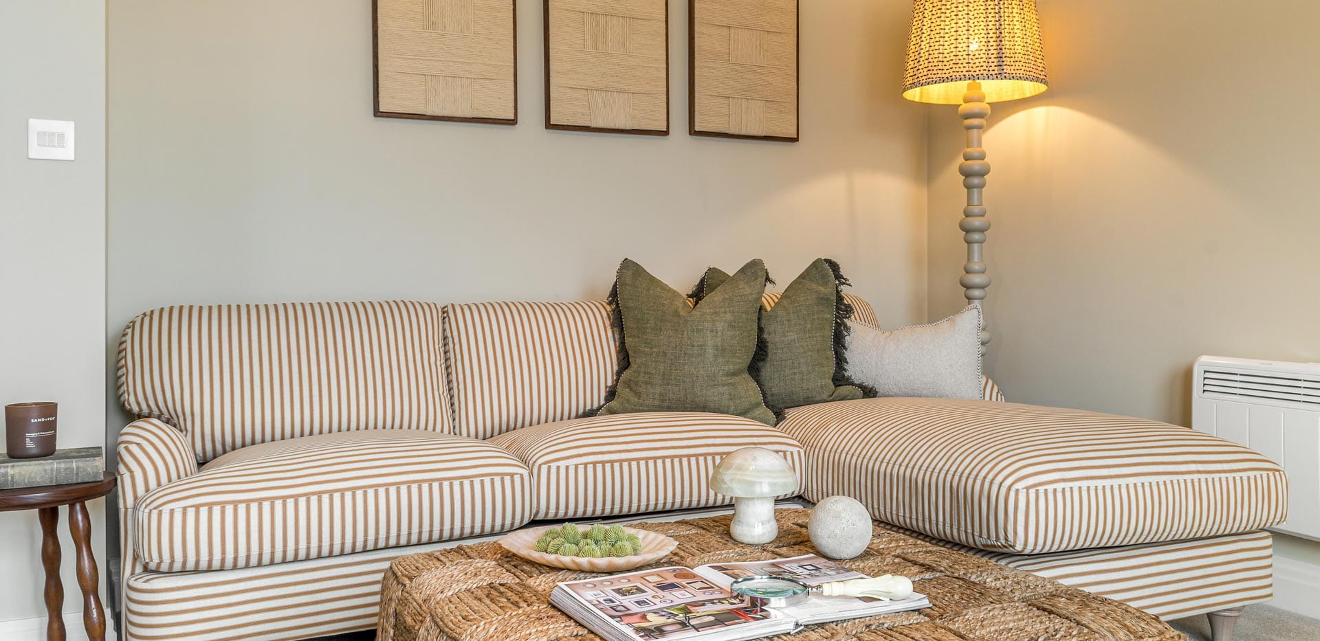 Living space showing a lounge sofa and coffee table, beige walls, wall hangings and floor lamp