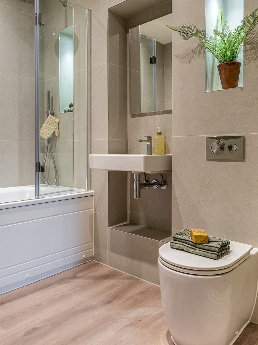 Bath over shower, wash basin and toilet, beige walls, with modern design and decorations