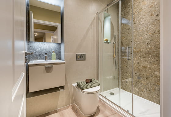 Shower unit with stone texture beige brown tiling, wash basin and wall mirror.