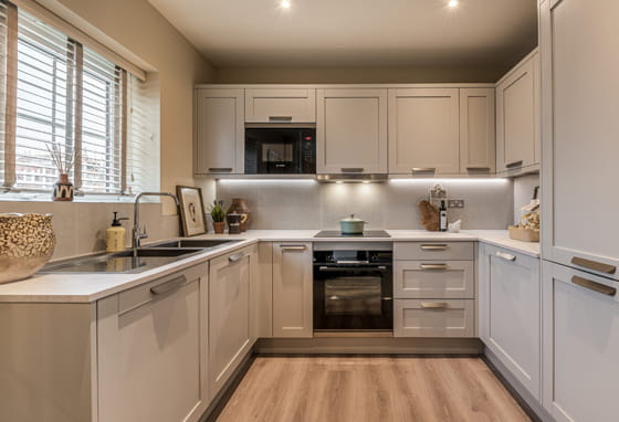 Kitchen with beige cupboard surfaces and white countertops.