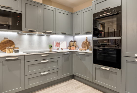 closeup of kitchen with light grey panels and cupboards, white countertops.