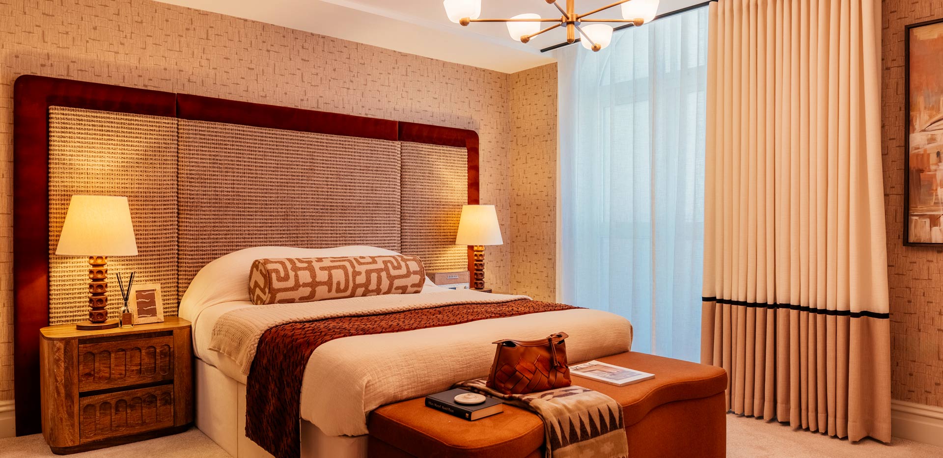 Double bed with modern design and décor, beige and red tones, floor to ceiling window.