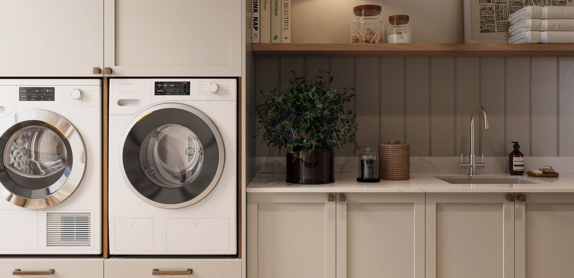 Front view of utility room showing two raised washing machines, sink adjacent and storage facilities