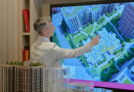 A salesperson presenting of a wide screen monitor of a development construction.